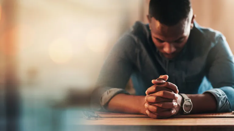 A man praying at a table.