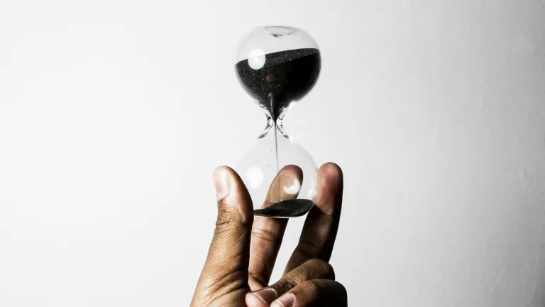 A person holding an hour glass with sand filtering down.