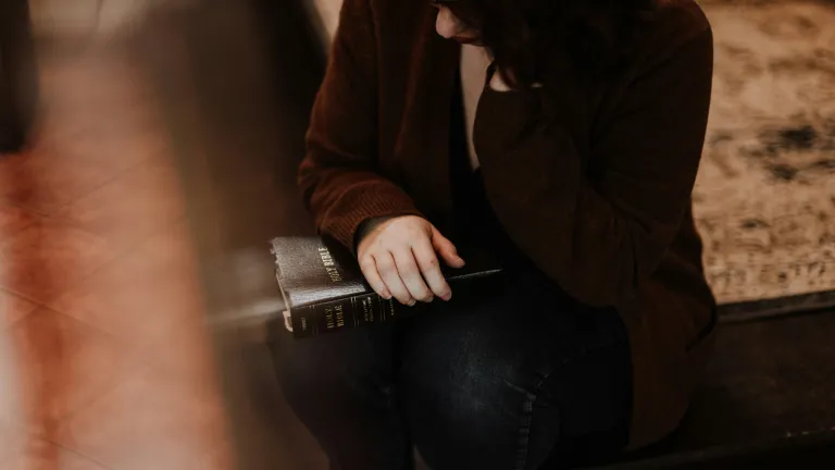 A woman sitting with a Bible on her lap.